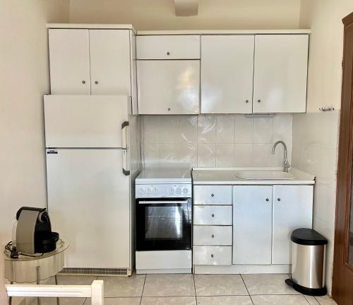 a kitchen with white cabinets and a refrigerator at Uranias Beach House in Kalives Poligirou