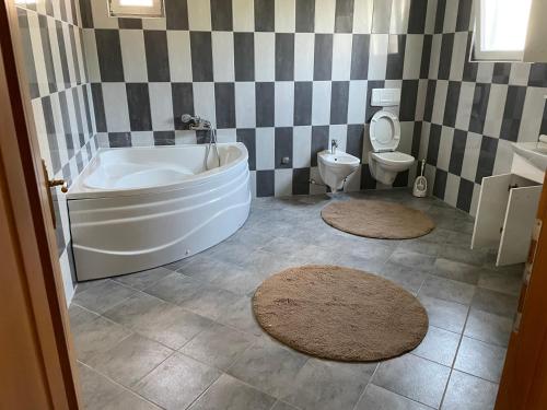een badkamer met een bad en een toilet met tapijten bij Cazin Centar Ćuprija in Cazin