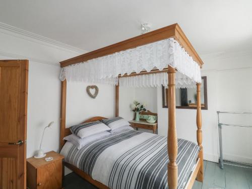 a bedroom with a bed with a wooden canopy at Driftwood in Exmouth