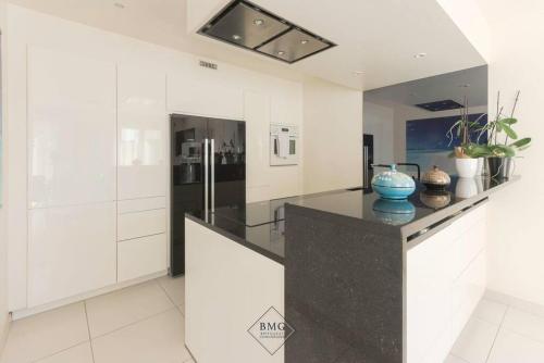 une cuisine avec des armoires blanches et un comptoir noir dans l'établissement Golf House Disneyland BMYGUEST, à Bussy-Saint-Georges