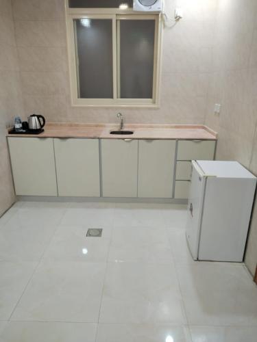 a white kitchen with a sink and a window at شقق هدوء الليالي للشقق المخدومة in Khamis Mushayt