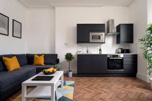 a living room with a blue couch and a kitchen at Torquay Heights Modern Apartments in Torquay
