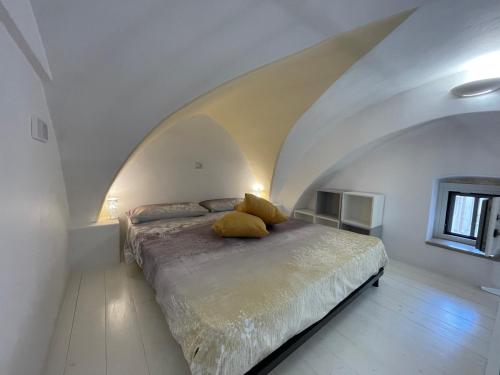 a bed with yellow pillows in a white room at Casa iuserì in Cisternino