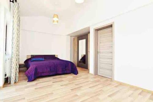 sypialnia z fioletowym łóżkiem i drewnianą podłogą w obiekcie Casa Albert w Jassach