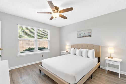 a white bedroom with a bed and a ceiling fan at Beach House - Moasis by Panhandle Getaways in Panama City Beach