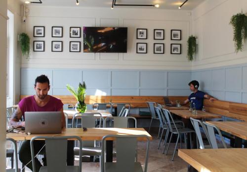 two men sitting at tables in a restaurant using a laptop at Sant Jordi Hostels Lisbon in Lisbon
