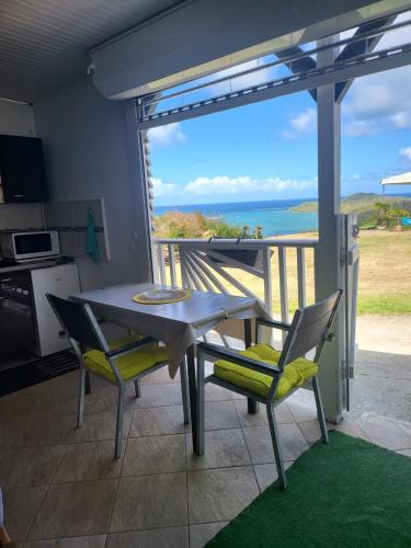 una mesa y sillas en una cocina con vistas al océano en Petit paradis location en Le Vauclin