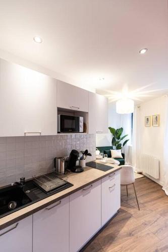 une cuisine avec des armoires blanches et un comptoir dans l'établissement Le refuge - Résidence Hestia, à Saint-Étienne