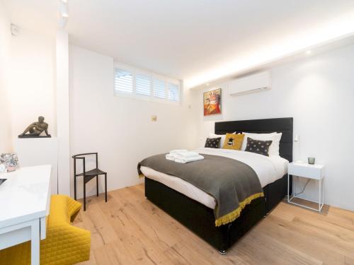 a bedroom with a large bed and a yellow chair at Modern Luxury 1 Bedroom Spacious Flat in London