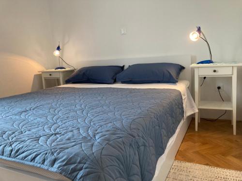 a bedroom with a bed with blue sheets and two tables at App Oljka in Karigador