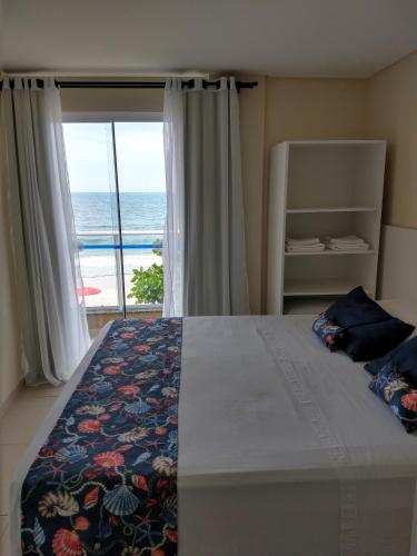 a bedroom with a bed with a view of the ocean at Pousada Bella Bombinhas - Pé na areia in Bombinhas