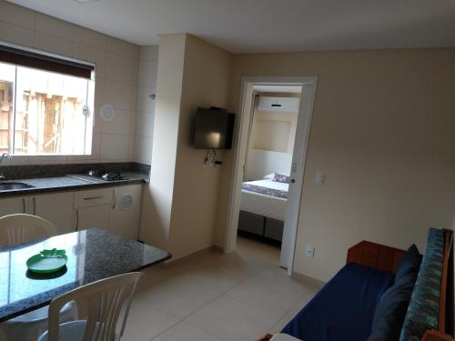 a living room with a table and a kitchen with a bed at Pousada Bella Bombinhas - Pé na areia in Bombinhas