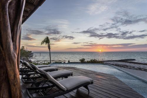 a group of chairs sitting on a deck near the ocean at DK Luxury Ocean Front Villa - Adults Only in Holbox Island