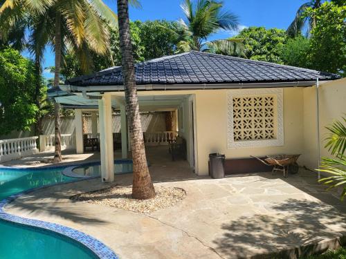 a house with a swimming pool and a palm tree at LeoMar 2 Diani Beach Ferienhaus mit grossen tropischen Garten und Pool in Ukunda