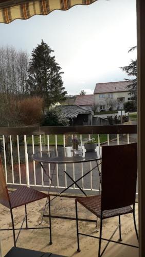 a table and chairs on a balcony with a view of a house at Gîte Le bel Epi in Vany