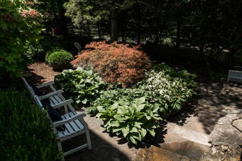 a garden with two white benches and flowers at Thomas Hart Benton at Southmoreland on the Plaza in Kansas City