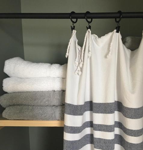 une étagère avec des serviettes et un rideau dans une salle de bain dans l'établissement QUAI 77•St Valery Centre •VUE DIRECTE BAIE - 6/12 pers, à Saint-Valery-sur-Somme