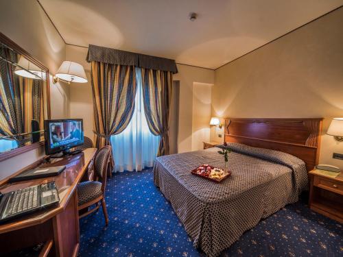 una camera d'albergo con letto e scrivania con computer di Hotel Valdarno a Montevarchi