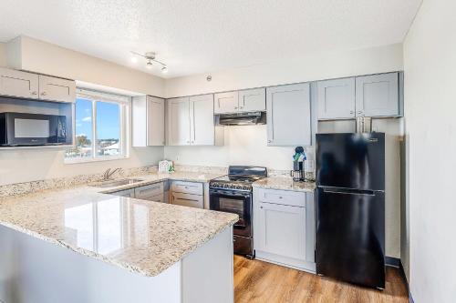 a kitchen with white cabinets and a black refrigerator at Sugar Sands Beachfront Hotel, a By The Sea Resort in Panama City Beach