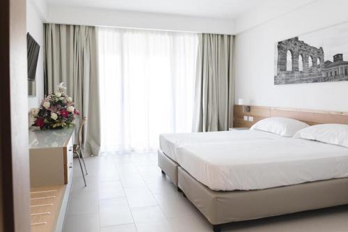 Un dormitorio con una cama y una mesa con flores. en Villa Ersilia, en Soverato Marina