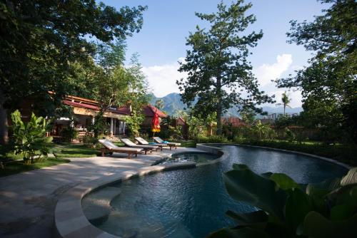 a swimming pool in a yard with benches around it at Kuda Laut Bungalows & Diving in Pemuteran