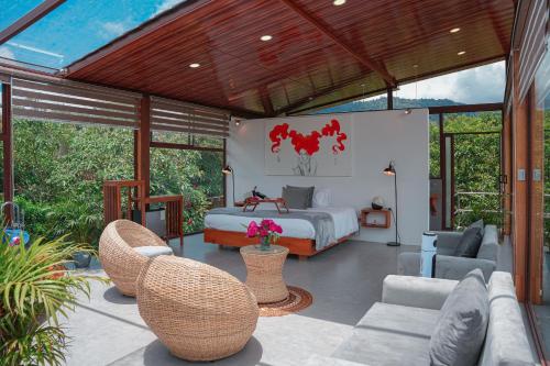 a bedroom with a bed and a couch and chairs at Coffee Lodge Cristal Glamping & Spa in Mindo