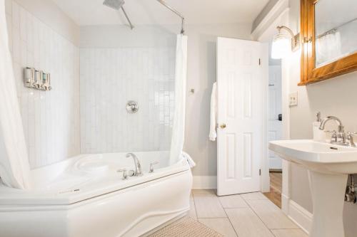 a white bathroom with a tub and a sink at Clara and Russell Stover at Southmoreland on the Plaza in Kansas City