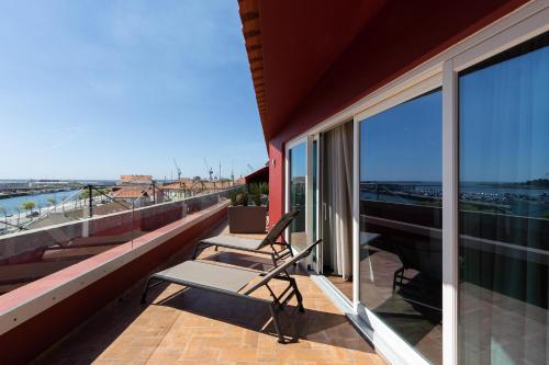 a balcony with a chair and a view of the ocean at AP Dona Aninhas in Viana do Castelo