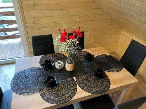 a wooden table with plates and a vase of flowers at Apartament na poddaszu u Reni in Grywałd