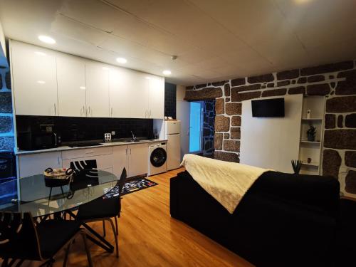 a kitchen and a living room with a glass table at Alojamento Local F&B in Guimarães