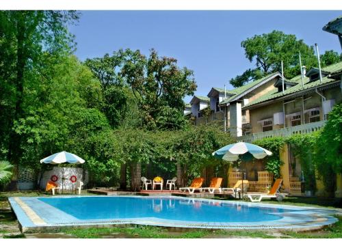 uma piscina com cadeiras e guarda-sóis ao lado de uma casa em WelcomHeritage Taragarh Palace em Kangra