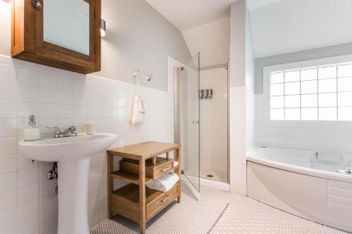 a white bathroom with a sink and a tub and a toilet at George Kessler Suite at Southmoreland on the Plaza in Kansas City