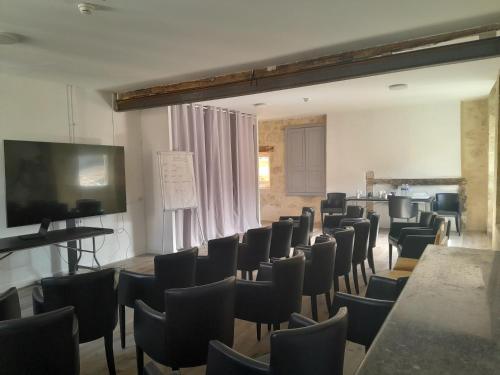 a room with a bunch of chairs and a flat screen tv at Hôtel de France in Auch
