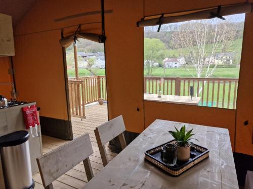 einen Tisch und Stühle in einer Küche mit Blick auf eine Terrasse in der Unterkunft Lodgetent Reisdorf in Reisdorf