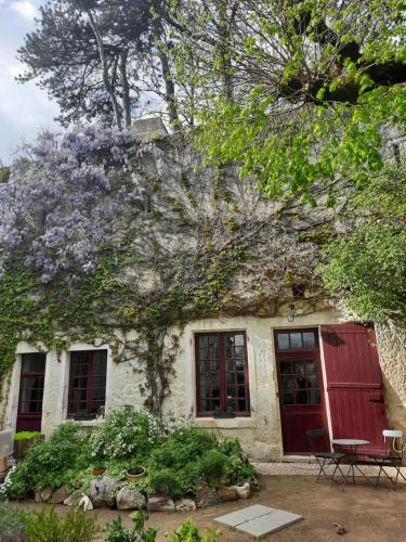 uma casa com uma porta vermelha e flores roxas em Les Tamayas em Noizay