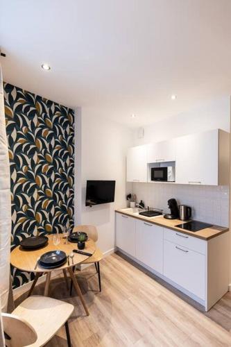 une cuisine avec des armoires blanches et une table et des chaises dans l'établissement Le Belvédère - Résidence Hestia, à Saint-Étienne