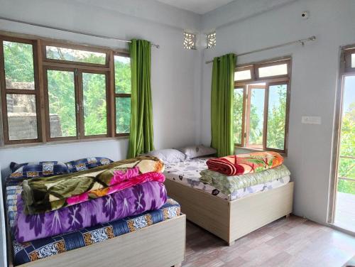 duas camas num quarto com cortinas verdes em Prakriti Homestay em Mangpu