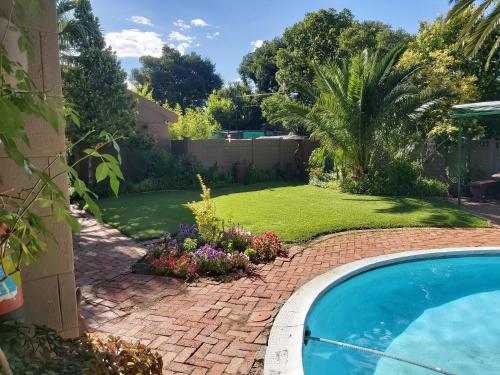einen Hinterhof mit Pool und Rasen in der Unterkunft Arista Guesthouse in Bloemfontein