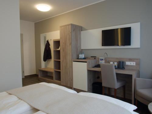 哈倫的住宿－格瑞酒店，酒店客房配有一张床、一张书桌和一台电视。