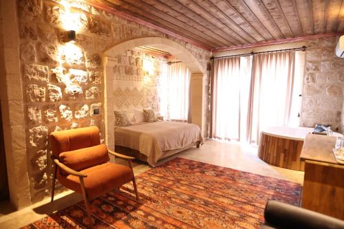 a bedroom with a bed and a chair and a tub at Cappadocia Vita Cave Hotel in Urgup