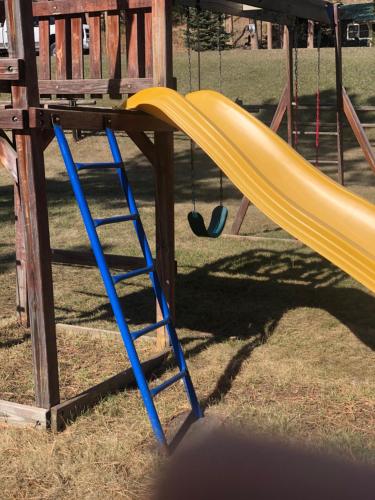 a yellow slide in a playground with a ladder at Black Hills Motel at Quail's Crossing in Hill City