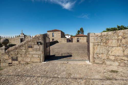 a stone wall with a gate in front of a building at Casa de Fervença in Espesês