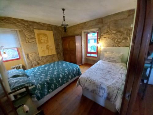 1 dormitorio con cama y pared de piedra en A CASA de FLORINDA, en Oia