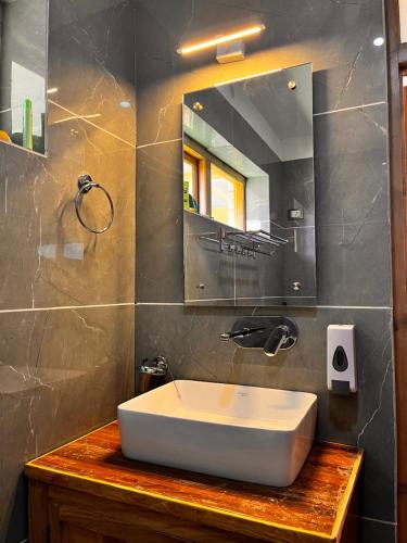 La salle de bains est pourvue d'un lavabo blanc et d'un miroir. dans l'établissement Ladakh Country Inn, à Leh