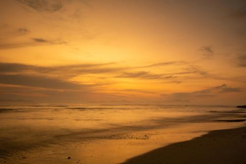 a sunset on the beach with the sand and water at Ocean Breeze Hotel in Strand