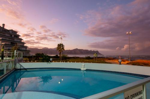 a swimming pool with a view of the ocean at Ocean Breeze Hotel in Strand