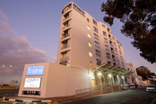 a tall building with a sign in front of it at Ocean Breeze Hotel in Strand