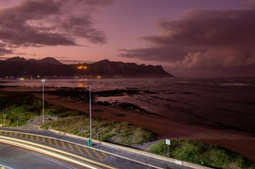 a road next to the ocean at night with mountains at Ocean Breeze Hotel in Strand