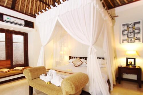 a bedroom with a bed and a chair with a canopy at The Amasya in Seminyak