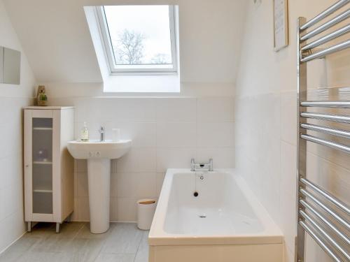 a white bathroom with a sink and a bath tub at The Barn in Llangwm